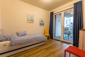 Ein Schlafzimmer mit Bett, Stuhl, Bank und einer Glastür zum Außenbereich.