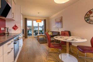 A modern kitchen with a dining area, a large window, and a clock on the wall.