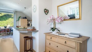 Une cuisine avec un tabouret de bar en bois, une commode en bois avec des tiroirs, un miroir et un décor en forme de cœur sur le mur.
