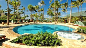 Une piscine entourée de palmiers et de chaises longues.
