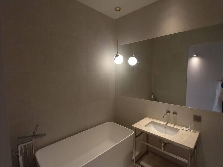 Un baño moderno con una bañera independiente, tocador con espejo e iluminación empotrada.
