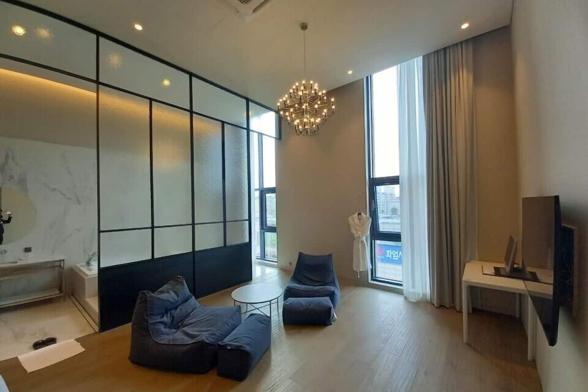 A modern living room with a sofa set, a small round table, a TV, and a large window with curtains.