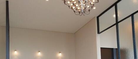 A modern hotel room with a large bed, a seating area with a table, and a chandelier.