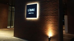 A sign for 'LIBRE HOTEL' illuminated against a brick wall at night. - Hotel Libre (Siheung)