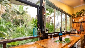 Een keuken met een houten aanrecht, een spoelbak en een raam met uitzicht op een tropische tuin.