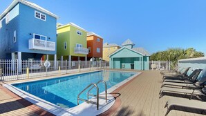 A swimming pool with a white fence, surrounded by colorful buildings and sun loungers. - "SummerTowne 1-At Pier Park"| Amazing Ocean Views | Dog-Friendly | Community Pool (Panama City Beach)