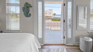 A bedroom with a large bed, a view of the beach, and a seahorse decoration on the wall. - "SummerTowne 1-At Pier Park"| Amazing Ocean Views | Dog-Friendly | Community Pool (Panama City Beach)