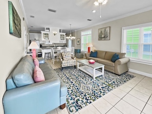 A living room with a sofa, armchair, coffee table, and a patterned rug.