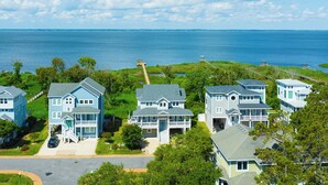 Een kustwoongebied met huizen met blauwe gevels, een helder uitzicht op zee en een verzorgd gazon.