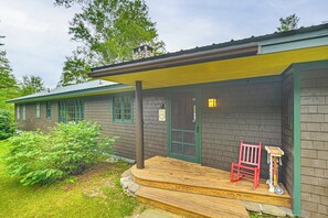 A building with a porch, a red chair, and a scooter. - Lakefront Escape w/ Deck & Kayaks in Lovell! (Lovell)