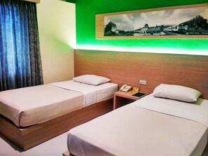 Habitación de hotel con dos camas individuales, una mesita de noche con teléfono y un cuadro en la pared.