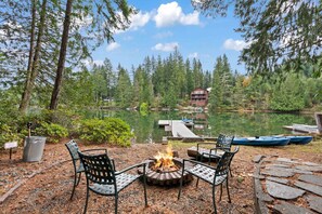 A lakeside patio with a fire pit, outdoor seating, and docked boats.