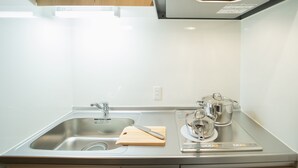 Eine moderne Küche mit Spüle aus Edelstahl, einem Holzschneidebrett und einem Wasserkocher.