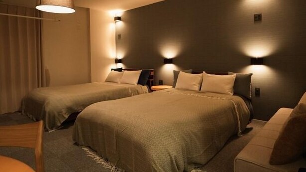 Ein Hotelzimmer mit zwei Betten, einer Schlafcouch und Wandleuchten.