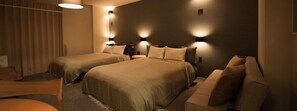 Ein Hotelzimmer mit zwei Betten, einer Schlafcouch und Wandleuchten.