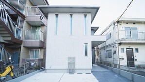 Ein modernes Gebäude mit Kachelfassade, einem gut sichtbaren Eingang und einem Fahrrad davor.