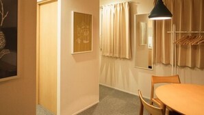 Ein Hotelzimmer mit einem Holztisch, einer Hängelampe, einem Garderobenhaken und einem gerahmten Bild an der Wand.
