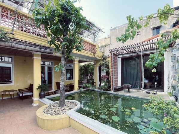 A courtyard with a small pond, seating areas, and a pergola.