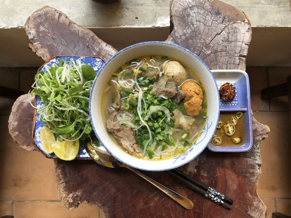Un tazón de sopa de fideos con carne, verduras, hierbas frescas y jalapeños rebanados.