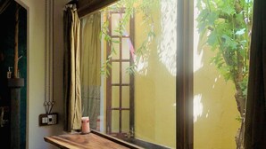 Ein Zimmer mit großem Fenster, einer hölzernen Bank und einem kleinen Tisch mit einem pinken Gegenstand.
