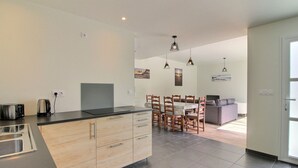 Une cuisine moderne dotée d’un îlot central, de meubles en bois et d’un coin repas avec une table et des chaises.