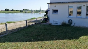 Ein weißes Gebäude mit umzäunter Fläche und einem Fluss im Hintergrund.