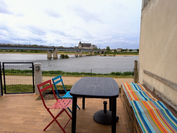 Un patio con tavolo e sedie, affacciato su un fiume e un ponte.