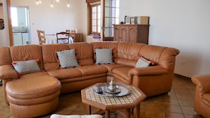 Ein Wohnzimmer mit einem braunen Ledersofa, einem runden Couchtisch und einem weißen, gepolsterten Hocker.