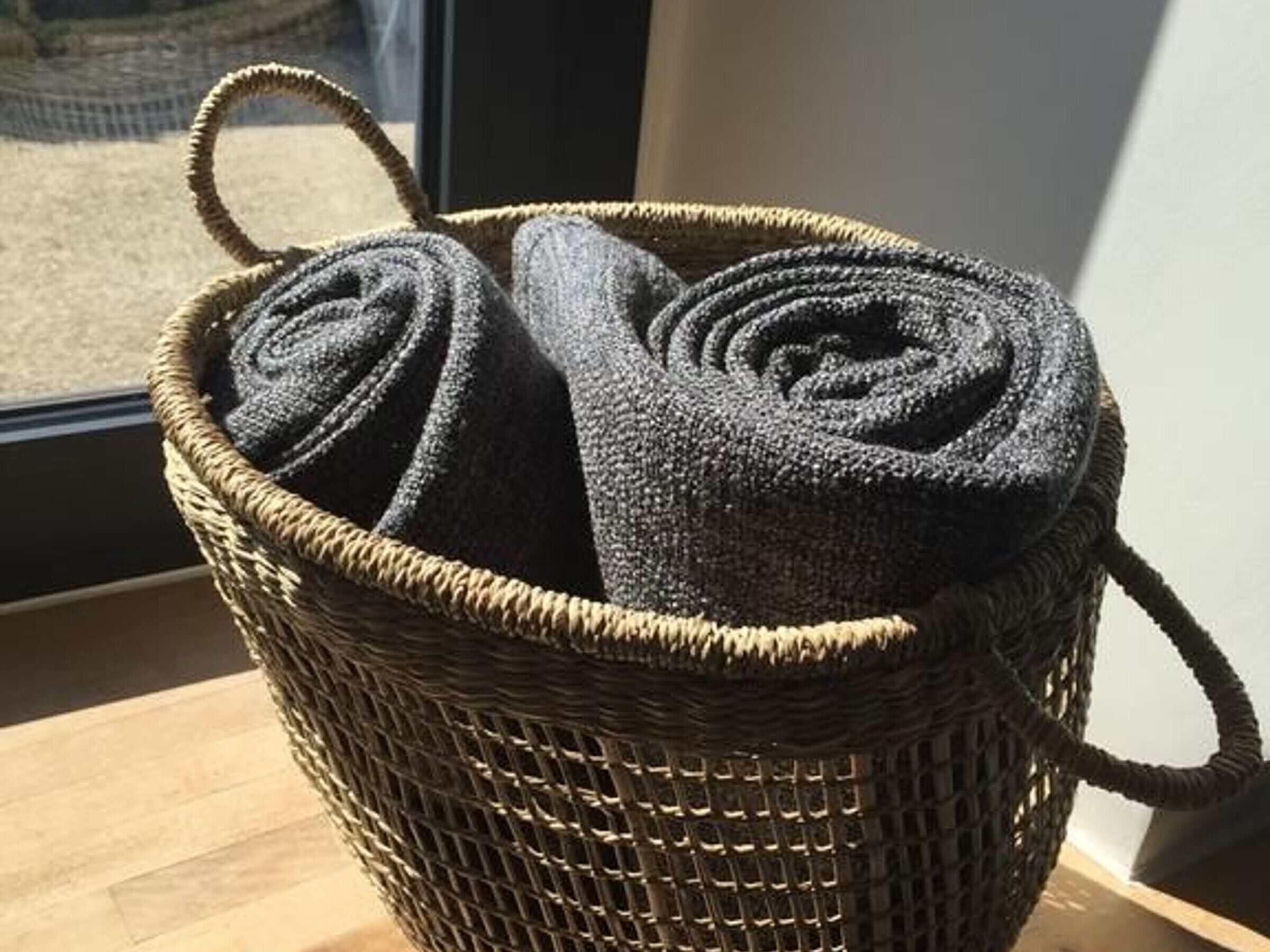 A woven basket with handles, containing rolled-up items.
