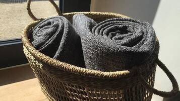 A woven basket with handles, containing rolled-up items.