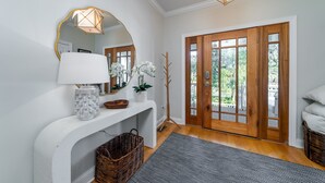 A hallway with a white console table, a mirror, a lamp, and a door with glass panels.