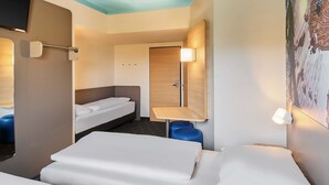 A hotel room with two beds, a small table, a chair, a wardrobe, and a TV. - B&B Hotel Darmstadt (Darmstadt)