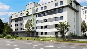A modern B&B hotel with a flat facade, multiple windows, and a prominent green sign. - B&B Hotel Darmstadt (Darmstadt)