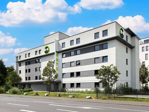 A modern B&B hotel with a flat facade, multiple windows, and a prominent green sign. - B&B Hotel Darmstadt (Darmstadt)