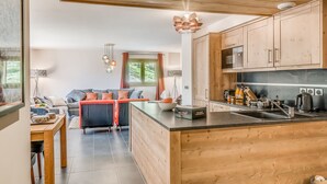 A modern kitchen with wooden cabinets, a central island, and a dining area with a sofa and table. - Luxury 5-room in Tignes, 8-10 people, hotel service (Tignes)