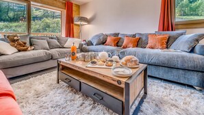 A modern living room with a sofa, a coffee table with breakfast items, and a view of the outdoors through large windows. - Luxury 5-room in Tignes, 8-10 people, hotel service (Tignes)