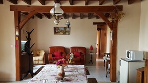 A dining area with a table set for two, two leather chairs, a floral tablecloth, a vase with flowers, and a ceiling fan.
