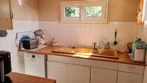 A kitchen with white cabinets, a wooden countertop, a Bosch dishwasher, a window above the sink, and various kitchen items.