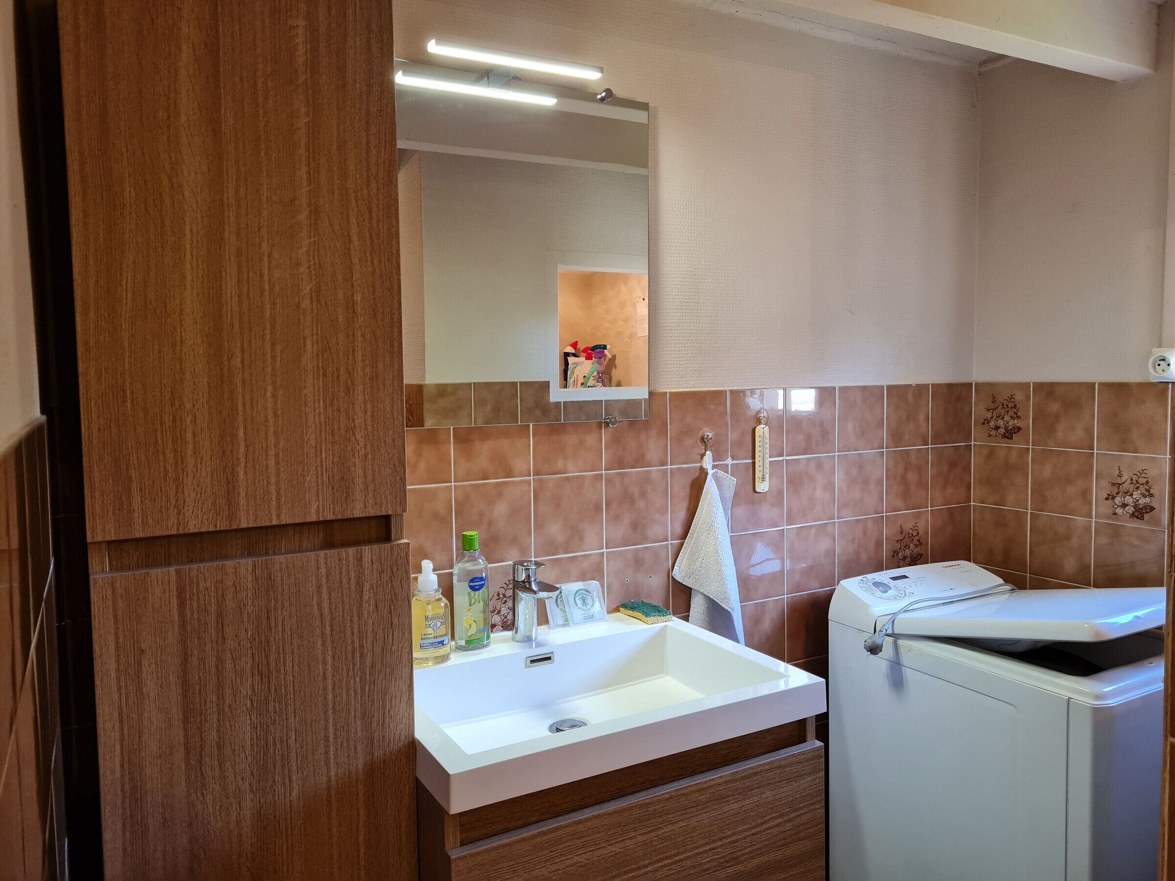 A bathroom with a white sink, a mirror, a towel rack, and a toilet.