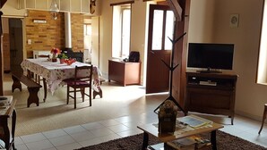 A cozy living room with a fireplace, a dining area with a table set for two, and a television on a wooden stand.