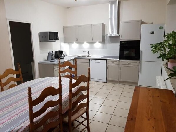 A compact kitchen with white cabinets, a microwave, a coffee maker, and a dishwasher.