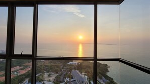 Vista de um arranha-céu para um corpo de água ao pôr do sol.