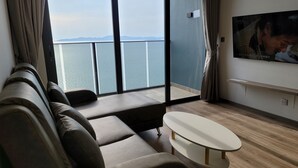 Uma sala de estar moderna com um sofá, uma mesinha e uma TV fixada na parede.
