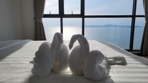 Cama com vista para o mar através de amplas janelas.