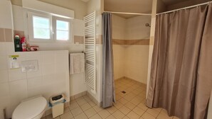Une salle de bain équipée de toilettes, d’une douche et d’un porte-serviettes.
