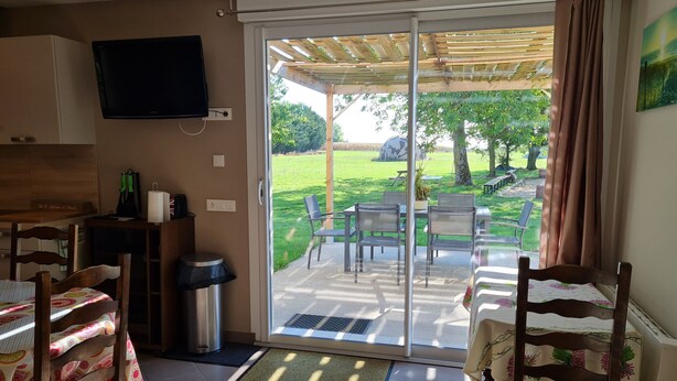 Une pièce dotée d’une porte-fenêtre coulissante donnant sur un patio extérieur avec des chaises et une table.