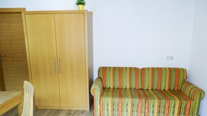 Une pièce avec une armoire en bois, un canapé à rayures et une chaise en bois.
