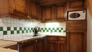 Eine Küche mit Holzausbau, einer Mikrowelle und einer gefliesten Spritzschutzwand.
