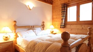 Ein Schlafzimmer einer Holzhütte mit einem Bett, zwei Nachttischen und einem Fenster mit Vorhängen.