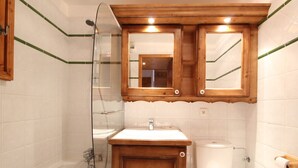 Ein Badezimmer mit einem Holzwaschtisch, einer weißen Toilette und einer gläsernen Duschkabine.